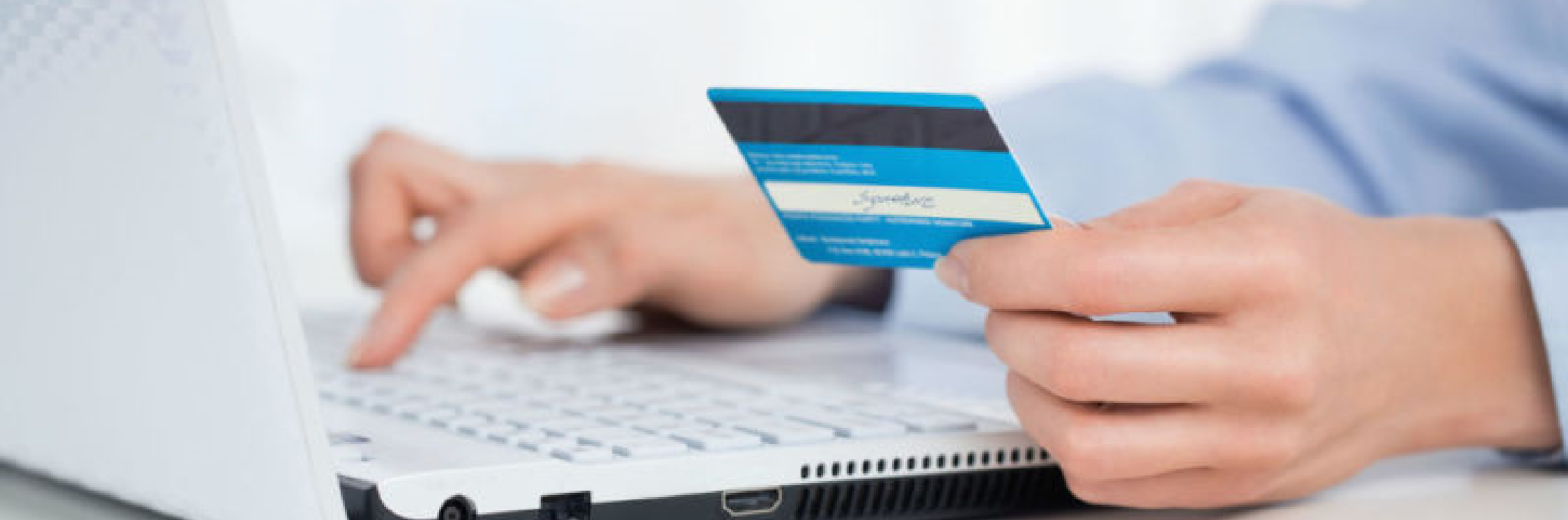 Man typing on laptop while holding a credit card
